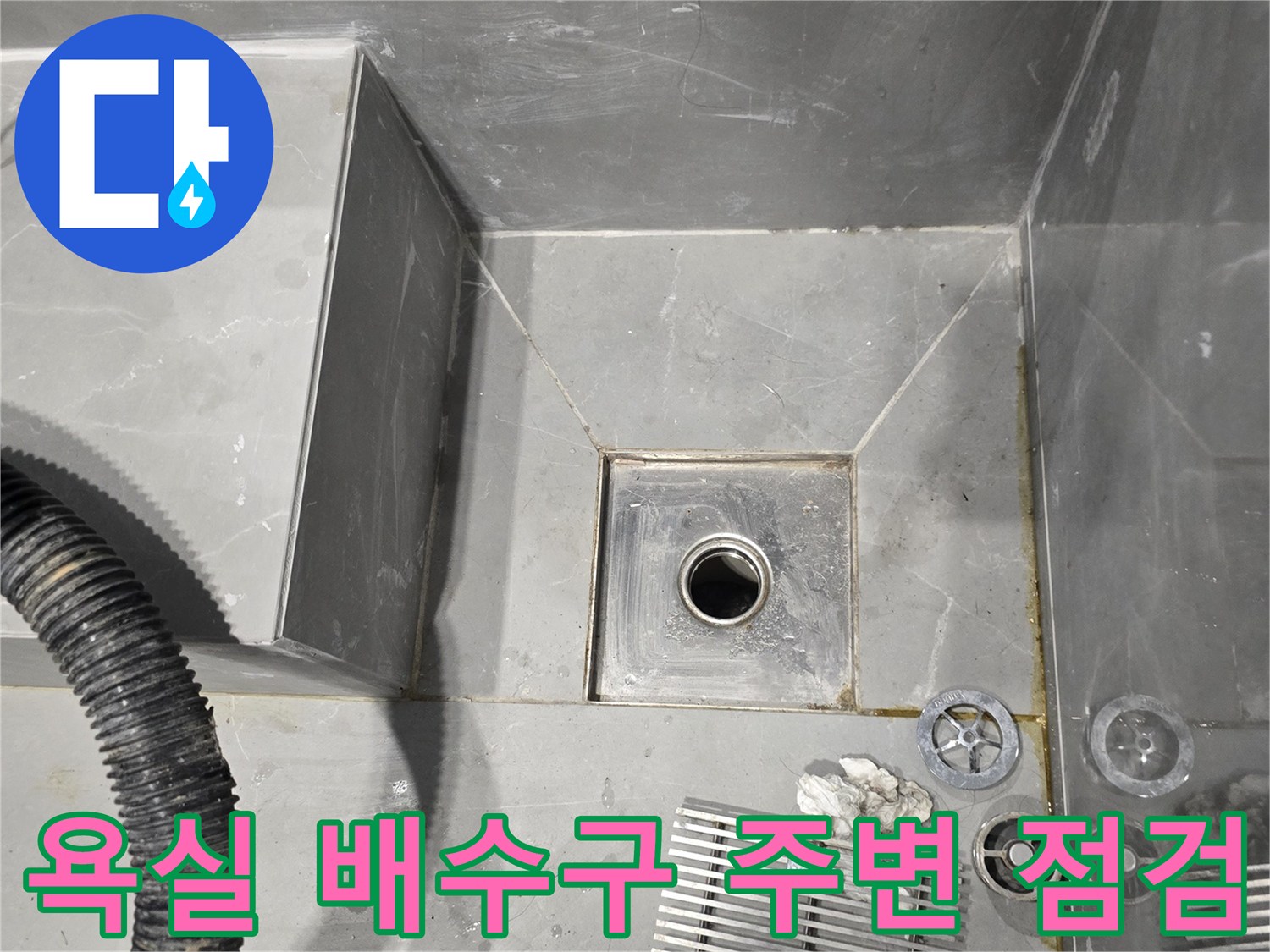 용인 수지구 빌라 욕실 바닥 배수구와 작업 도구가 놓여 있는 모습