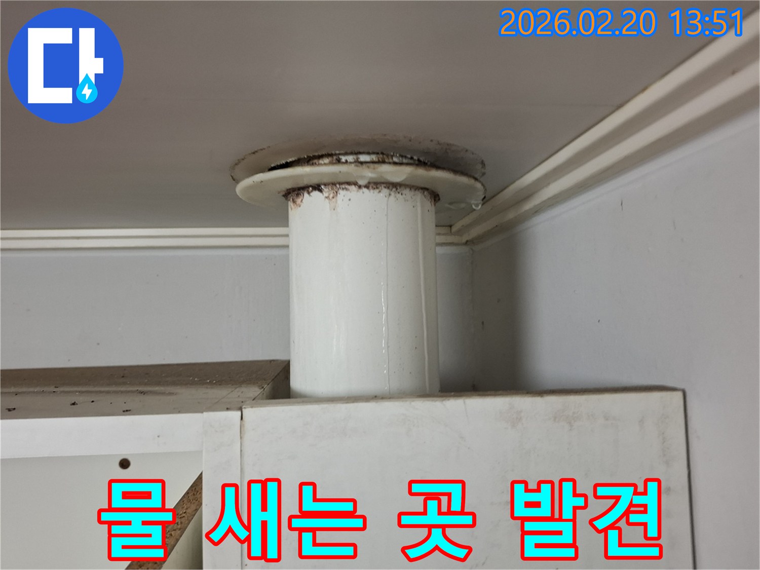 천장 아래 배관에서 물이 새면서-갈색 침전물과 함께 물방울이 맺힌 누수 현장입니다.