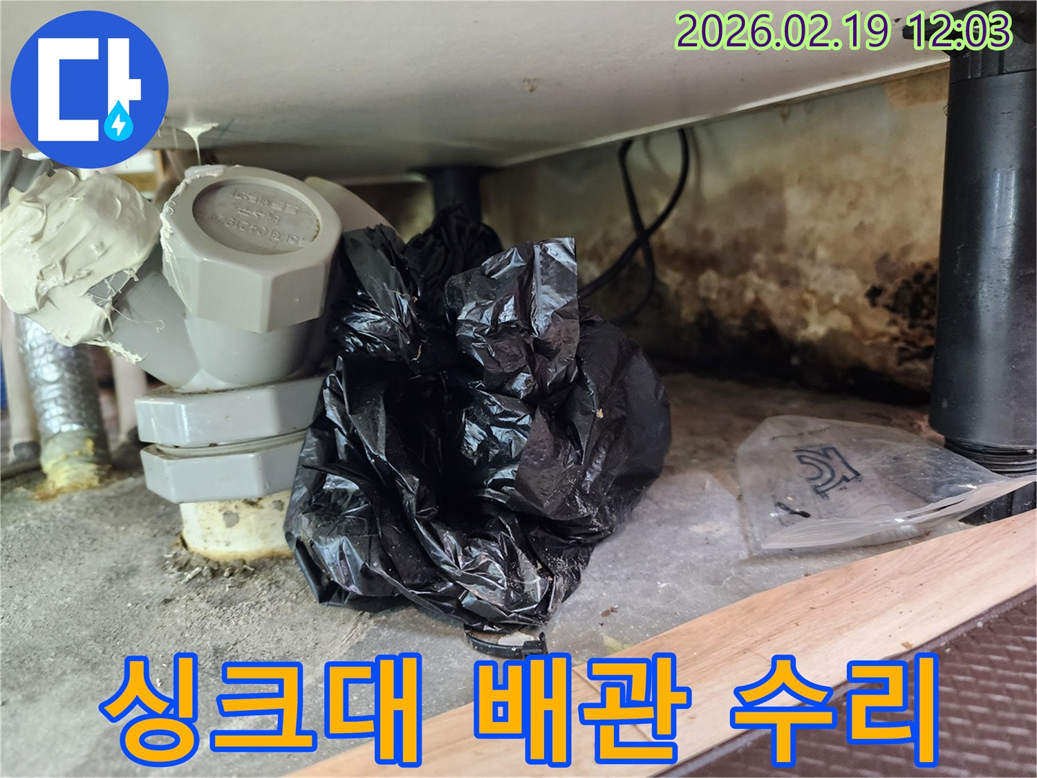 이 이미지는 싱크대 하부의 낡은 배관 부속과-누수로 인한 곰팡이-오염 상태를 보여줍니다.