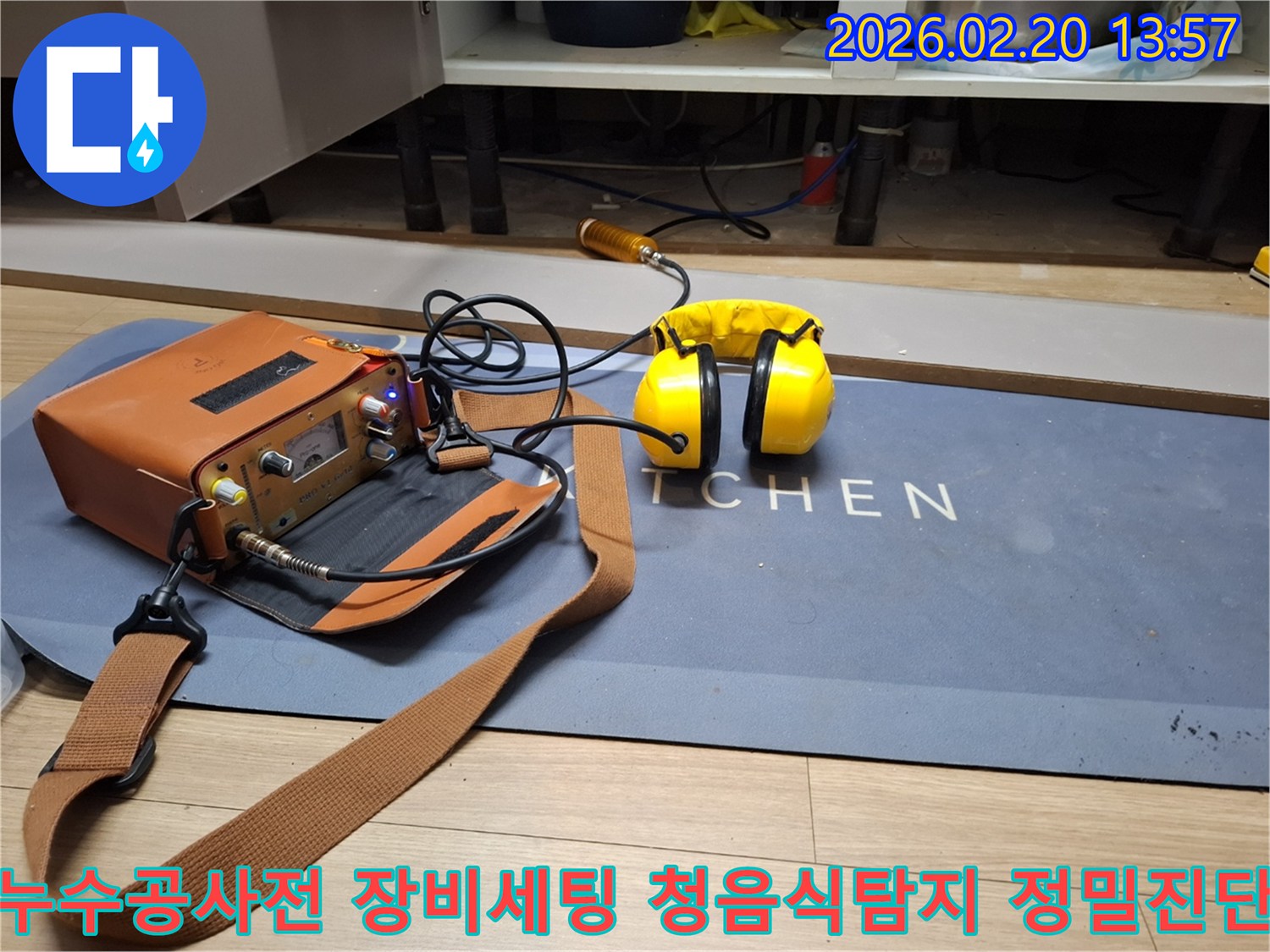 싱크대 아래에서 발생한 누수를 진단하기 위해-청음식 누수 탐지기와-작업자의 청각을 보호하는 헤드폰이 준비된 모습입니다