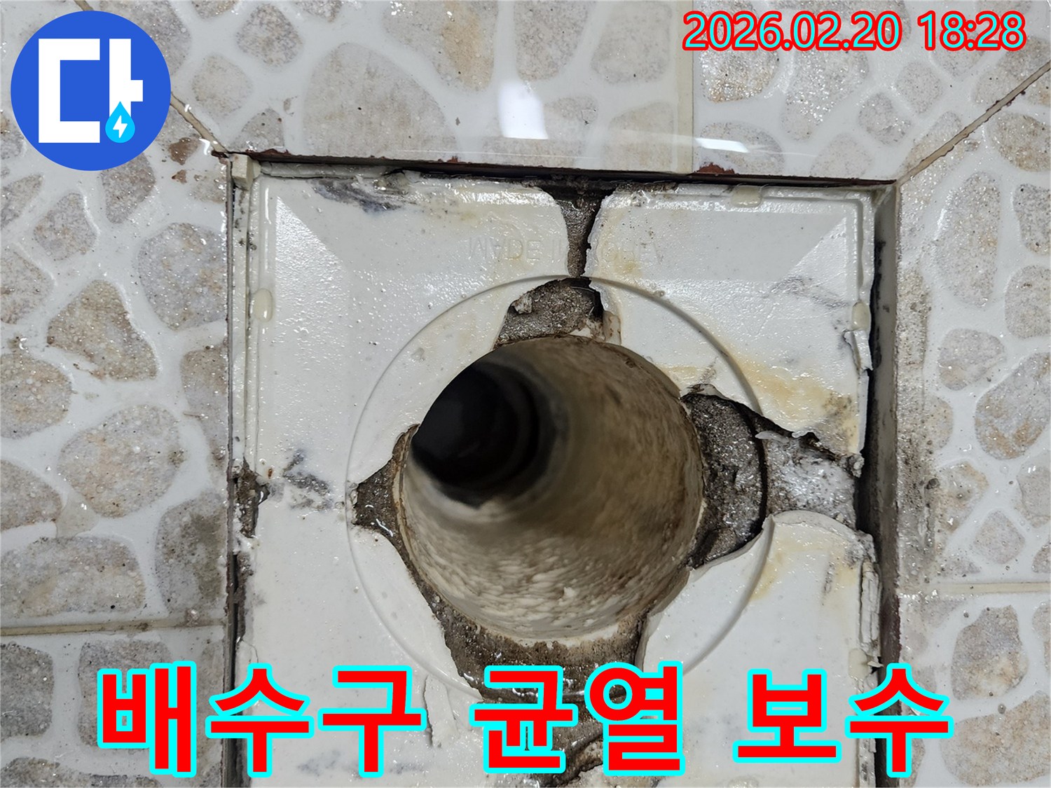 이 이미지는-욕실 배수구 주변의 심각한 균열로-누수가 발생하고 있는-현장을 보여주며-즉각적인 보수가 필요함을 나타냅니다