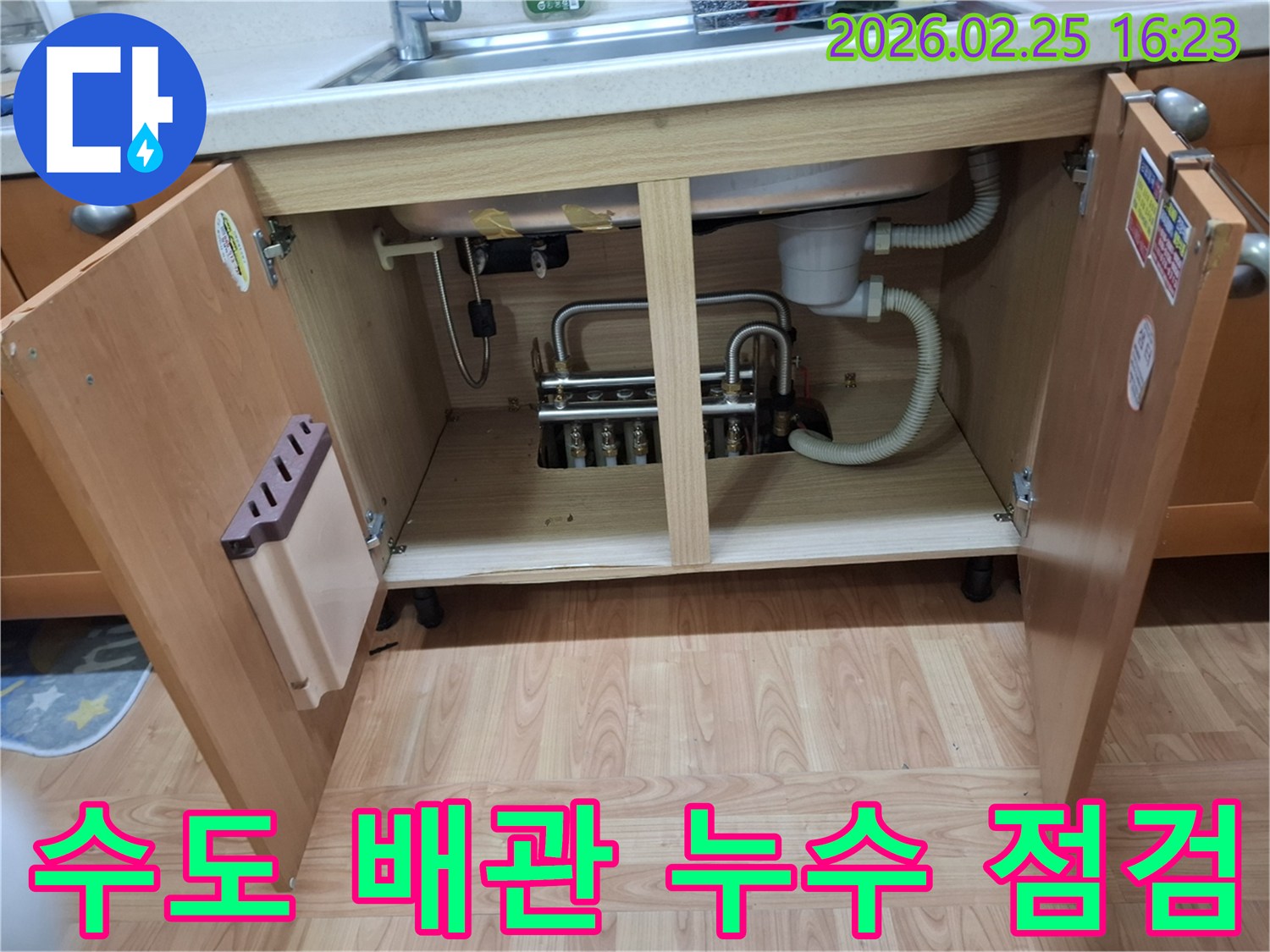 이 이미지는-김포 감정동 주택의-싱크대 하부장 내부에서-수도 배관의 누수 여부를-정밀하게 점검하고-수리하기 위해-준비하는 과정을-보여주고 있습니다