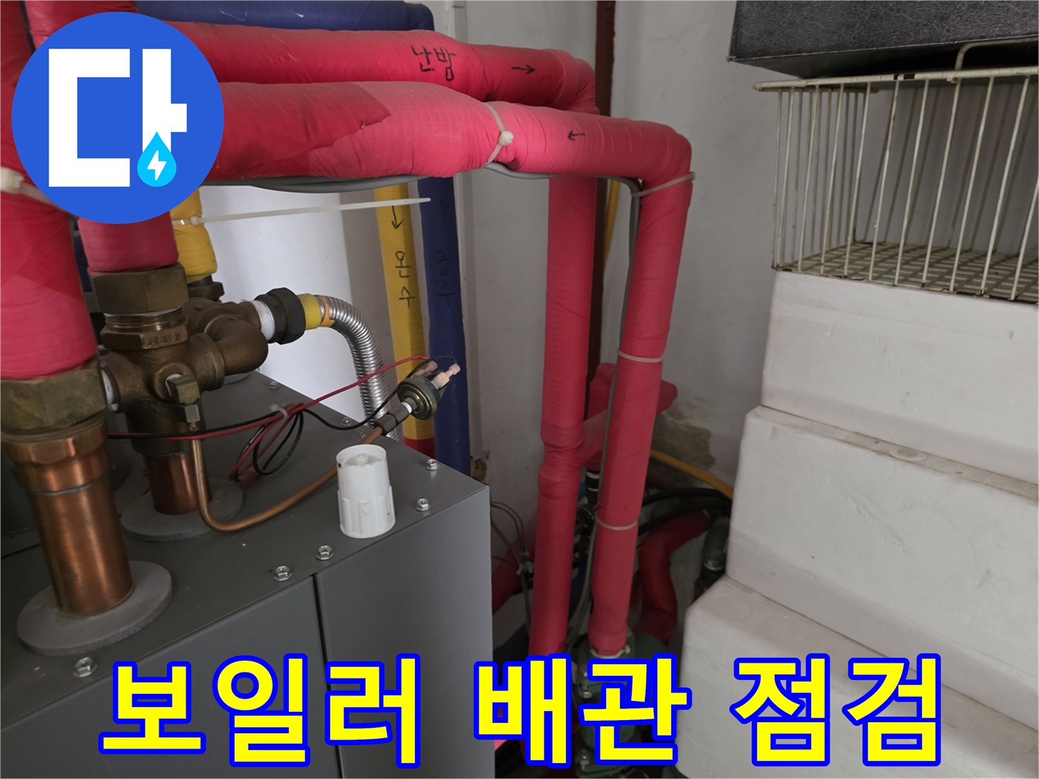 붉은색 보온재로 감싸진-난방용 배관과 장비가 설치된 모습입니다.