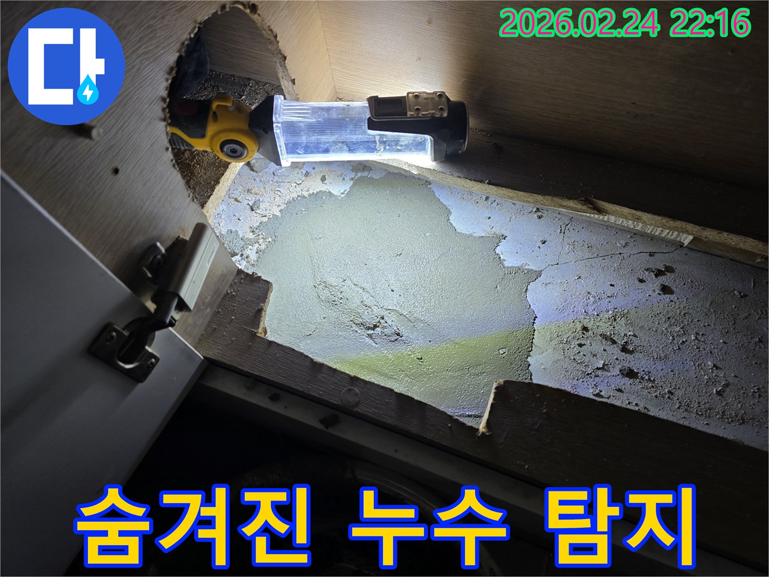 누수-엔지니어가-어두운-싱크대-하부에서-숨겨진-누수-지점을-찾기-위해-조명-장비를-사용하여-정밀-탐지하는-모습