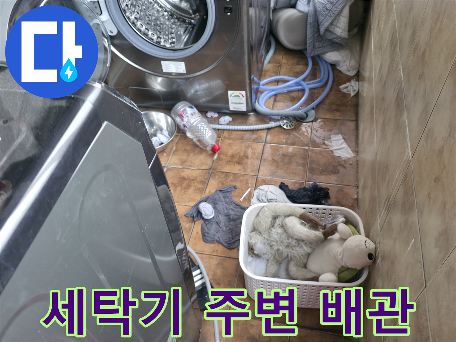 세탁기 뒤쪽으로 연결된 파란색 호스와 젖은 바닥의 모습입니다.