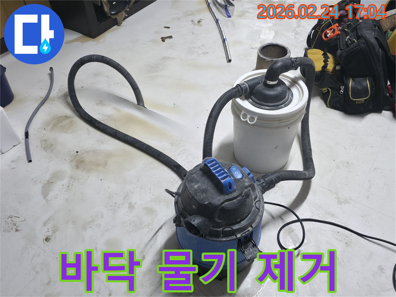 누수 현장에서 바닥에 고인 물을 신속하게 제거하는 전문 습식 청소기 사용 장면