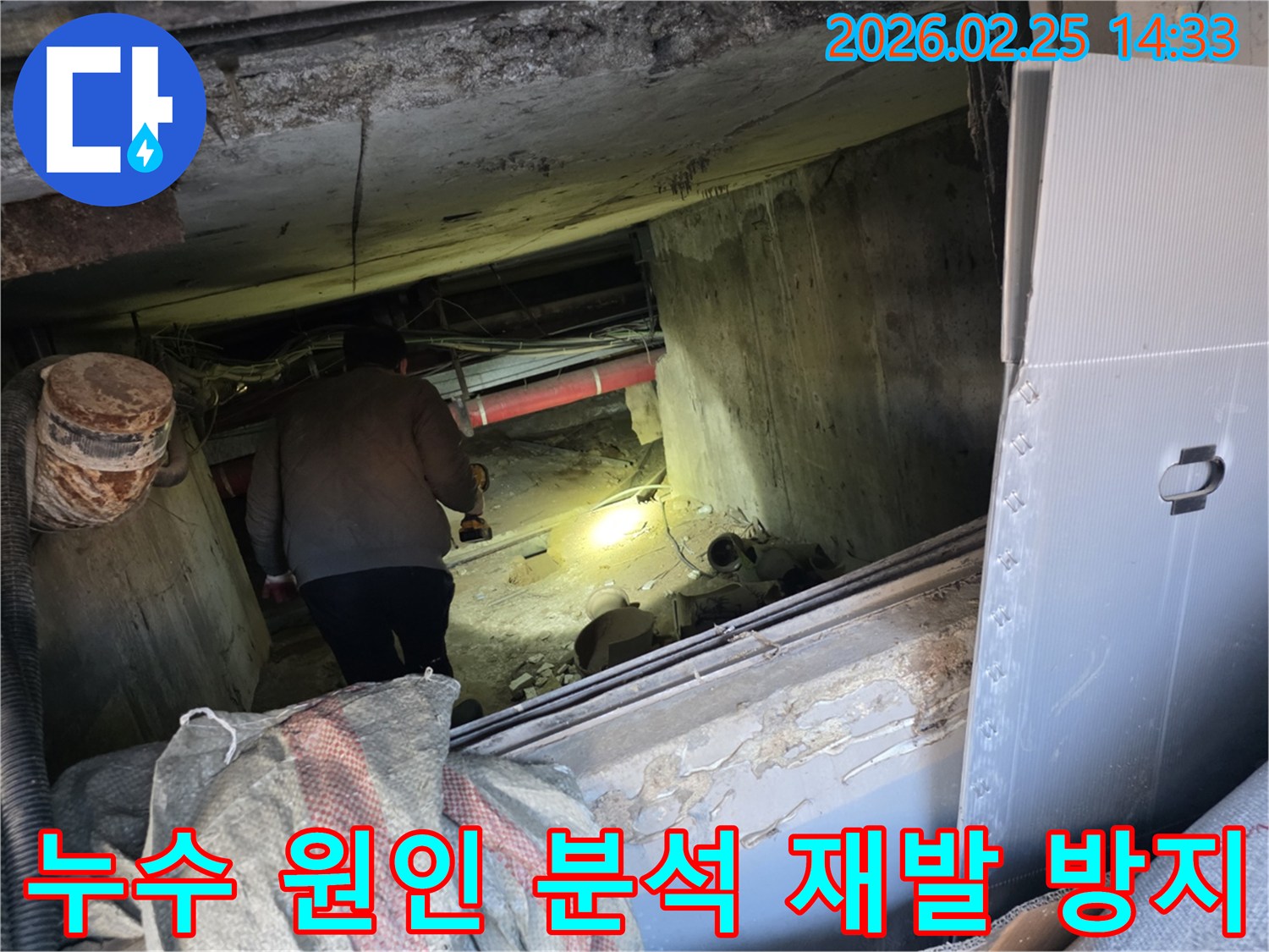 누수 전문 엔지니어가-손전등을 사용하여-어둡고 좁은 공간에서-배관의 누수 흔적을-세밀하게 탐지하며-재발 방지를 위한-원인 분석을 진행하는 모습입니다.