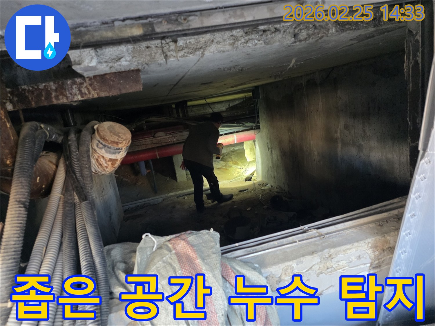 누수 전문가가-손전등을 비추며-배관이 복잡한-지하 통로를-조사하는 모습