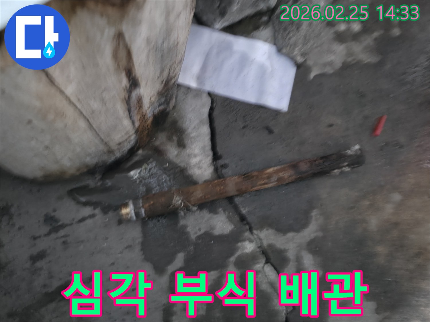 심하게 부식되어-파열된 오래된 배관이-젖은 바닥에 놓여있는-누수 공사 현장 사진입니다.