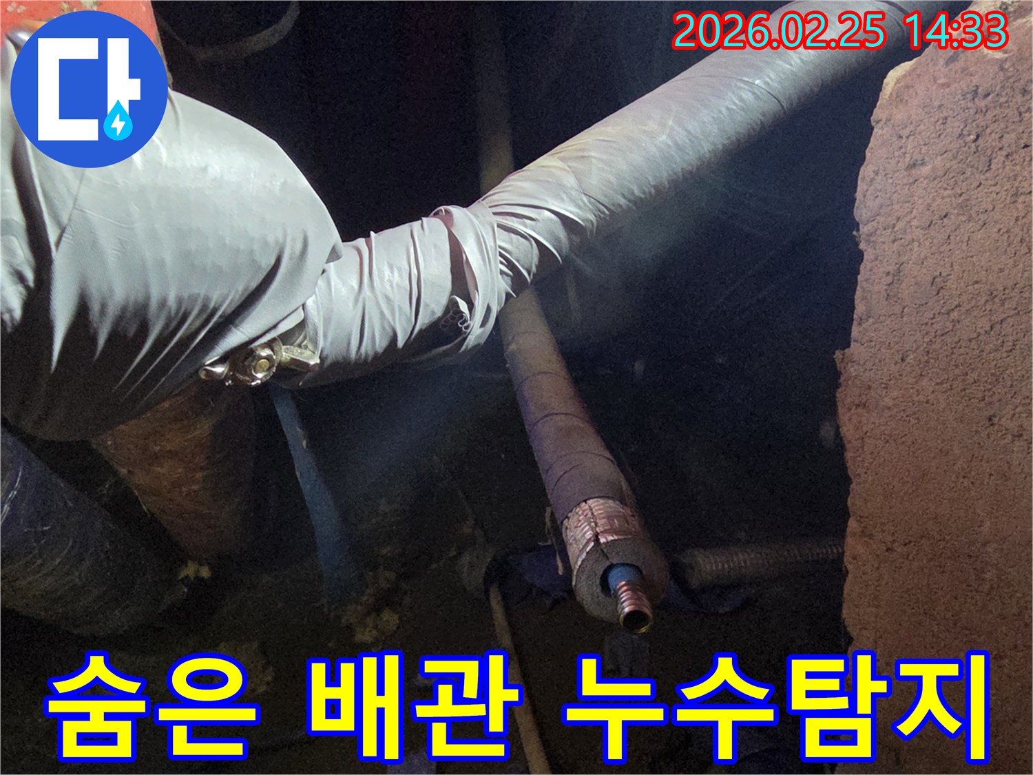 어두운 공간에서-장갑을 낀 손이-두꺼운 단열재로-둘러싸인 배관의-손상된 부분을-꼼꼼히 확인하며-누수 원인을-찾아내는 장면입니다
