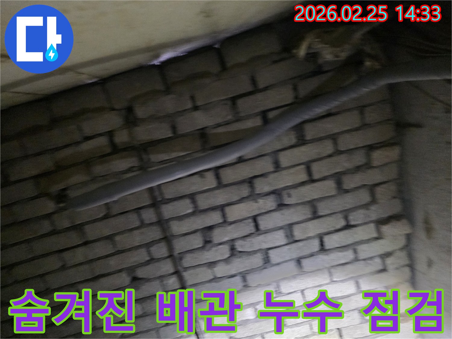 어두운 벽돌 벽면을 배경으로-단열된 배관과 함께-누수 여부를 확인하기 위해-정밀하게 검사되는 현장 모습입니다.