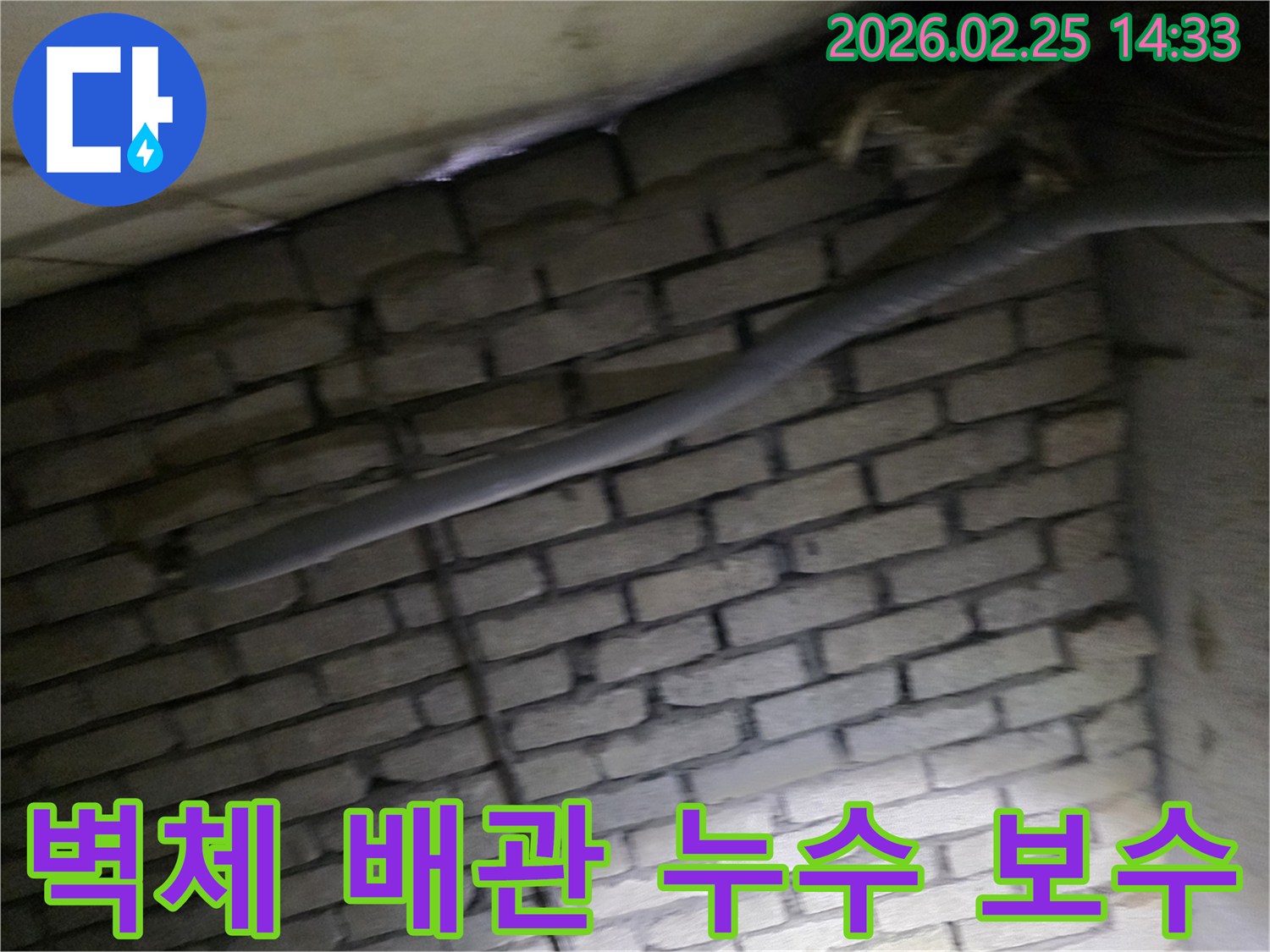 어두운 벽돌 벽면을 배경으로-단열된 배관과 함께-누수 여부를 확인하기 위해-정밀하게 검사되는 현장 모습입니다.