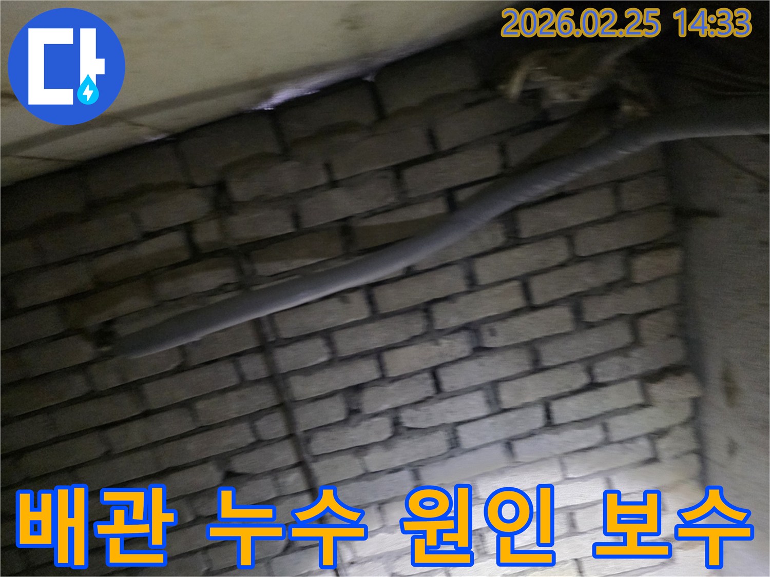 어두운 벽돌 벽면을 배경으로-단열된 배관과 함께-누수 원인을 파악하고-보수 작업을 준비하는 현장 모습입니다.