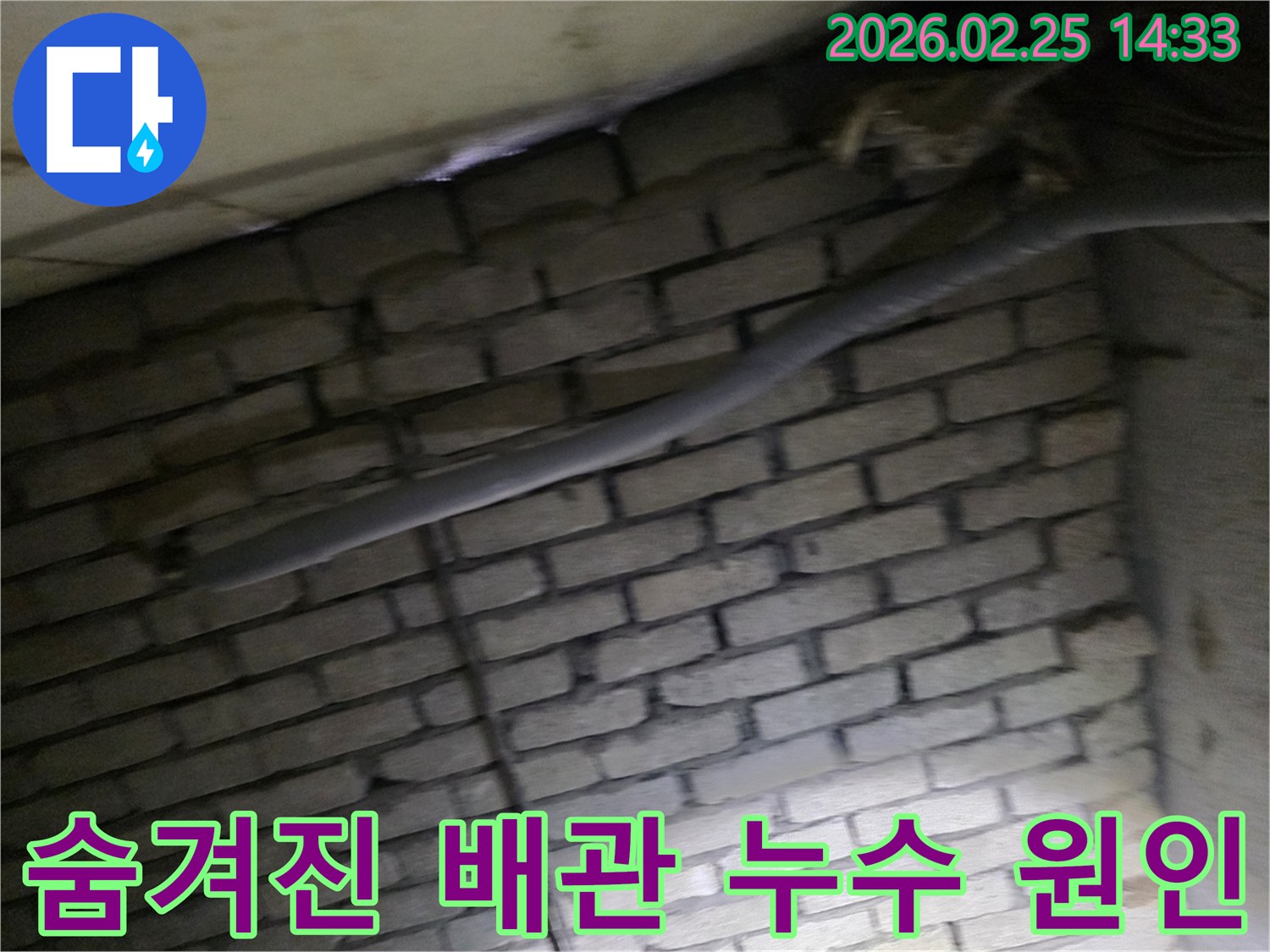 어두운 벽돌 벽면을 배경으로-단열된 배관과 함께-숨겨진 누수 원인을 파악하기 위해-정밀하게 검사되는 현장 모습입니다.