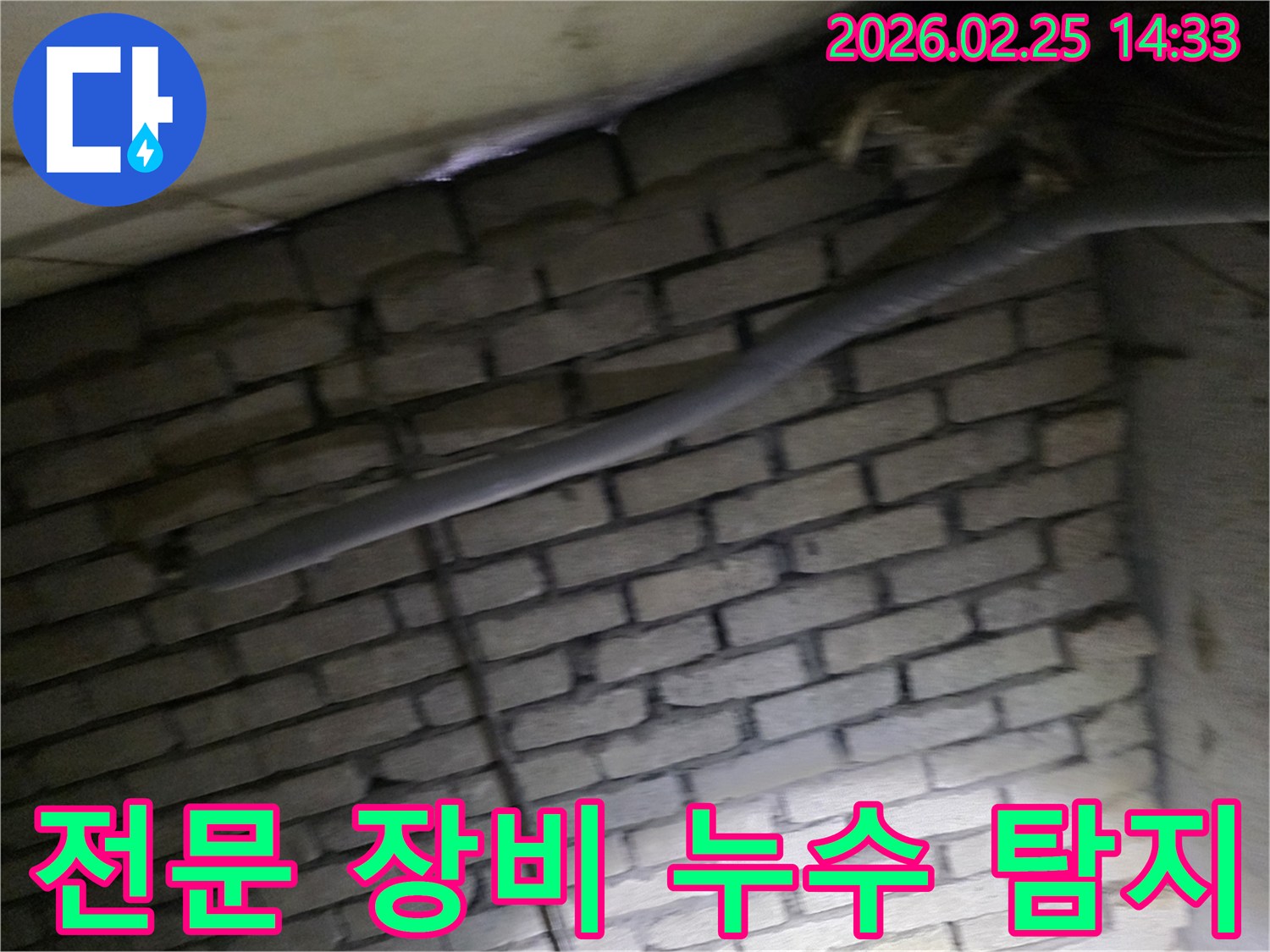 어두운 벽돌 벽면을 배경으로-단열된 배관에서 발생하는-누수를 전문 장비로-탐지하는 현장 이미지입니다.
