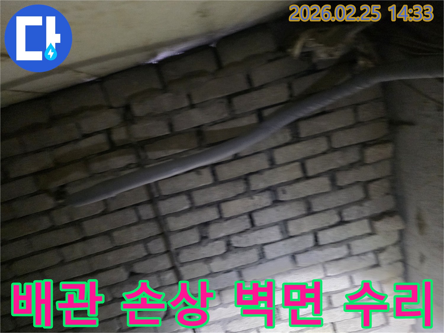 어두운 벽돌 벽면을 배경으로-손상된 배관과 함께-누수 수리 작업을 위해-정밀하게 검사되는 현장 모습입니다.