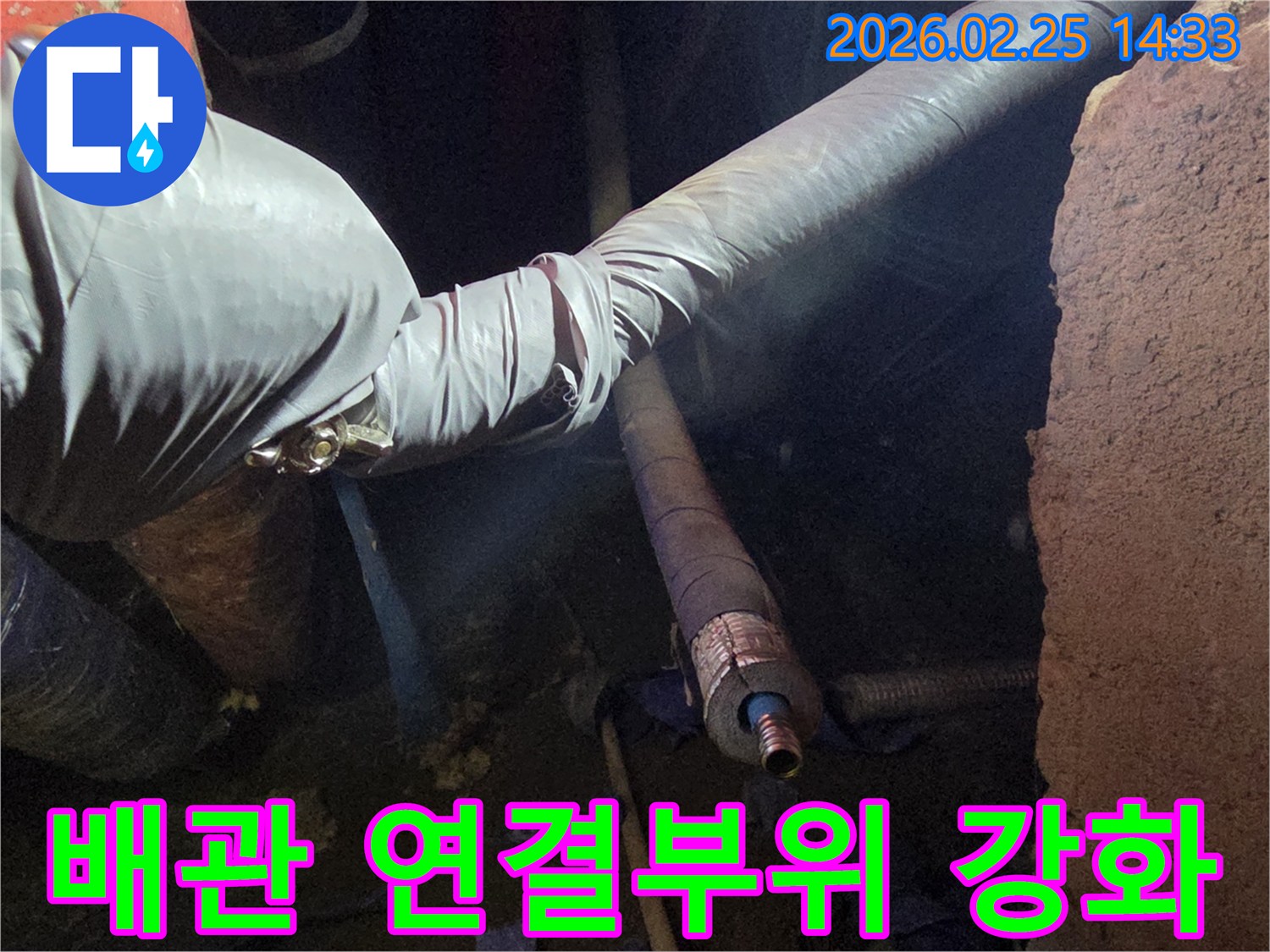 어두운 작업 공간에서-장갑을 낀 손이-손상된 배관의-연결 부위를-더욱 튼튼하게-강화하여-누수 재발을-방지하는 모습입니다