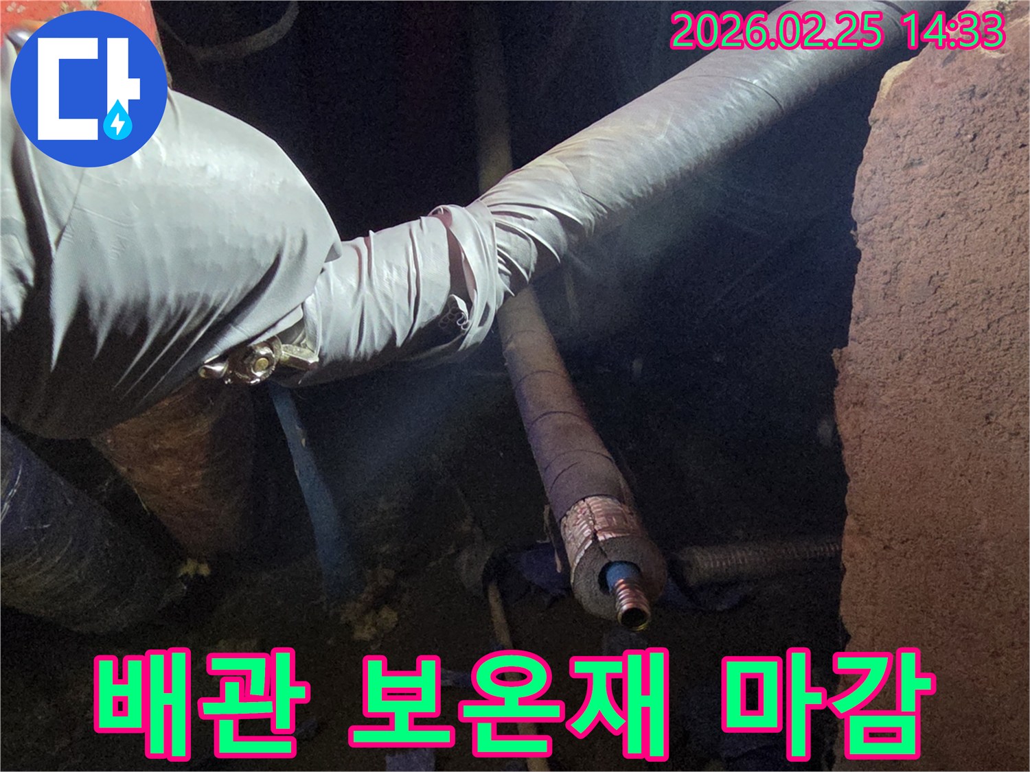 어두운 작업 공간에서-장갑을 낀 손이-수리된 배관에-새로운 보온재를-꼼꼼하게 감싸서-열 손실을 방지하는-모습입니다