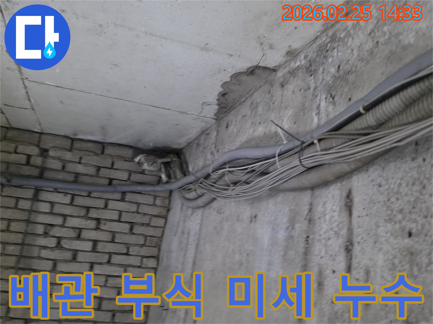 지하 벽면의-콘크리트와-벽돌 벽이 만나는-지점에서-발견된-오랜 누수로 인한-물자국과-주변의 복잡한 배관