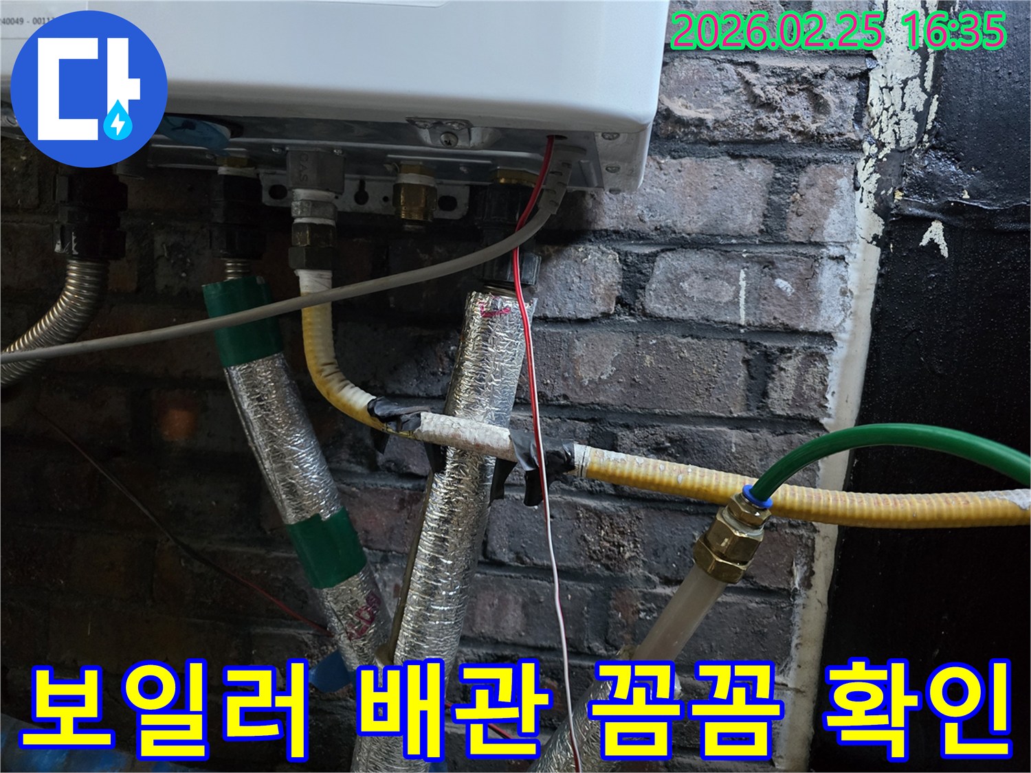 이 이미지는-벽에 설치된-보일러 하단부의-복잡한 배관 연결부와-전선-그리고-은색 단열재로-감싸진-파이프들을-보여주며-누수 점검을 위한-꼼꼼한 확인이-진행되고-있음을-암시합니다.