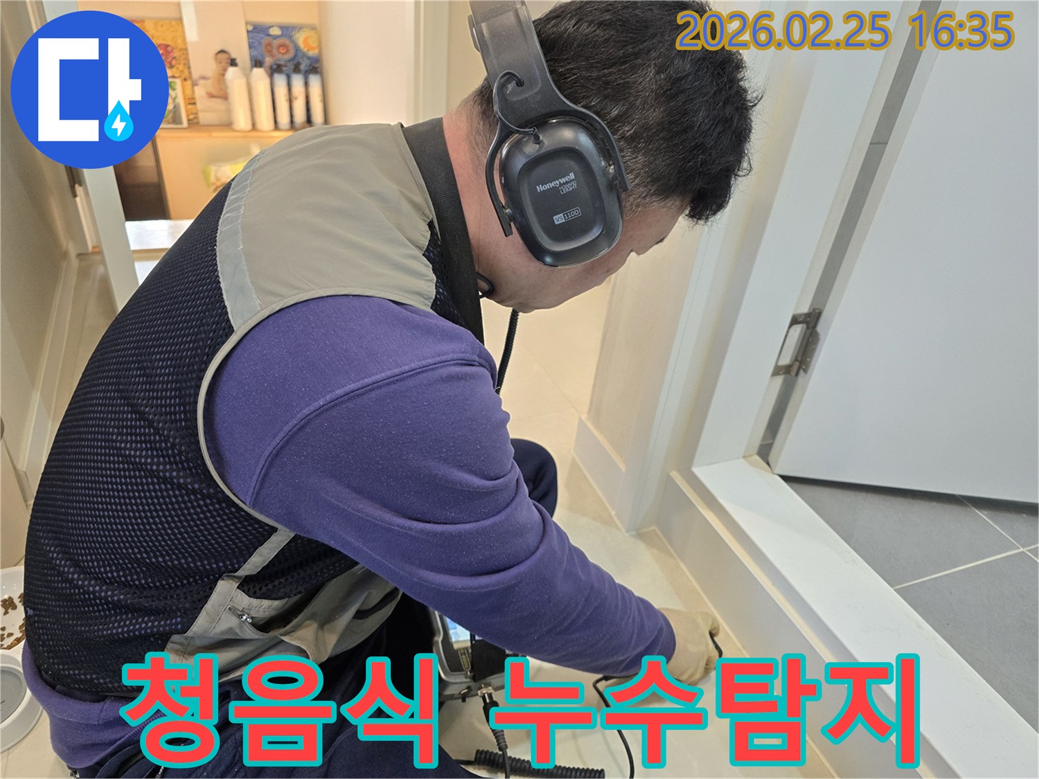 전문가가-헤드폰을 착용하고-누수 탐지 장비로-바닥의 미세한 소리를-듣고 있는 장면