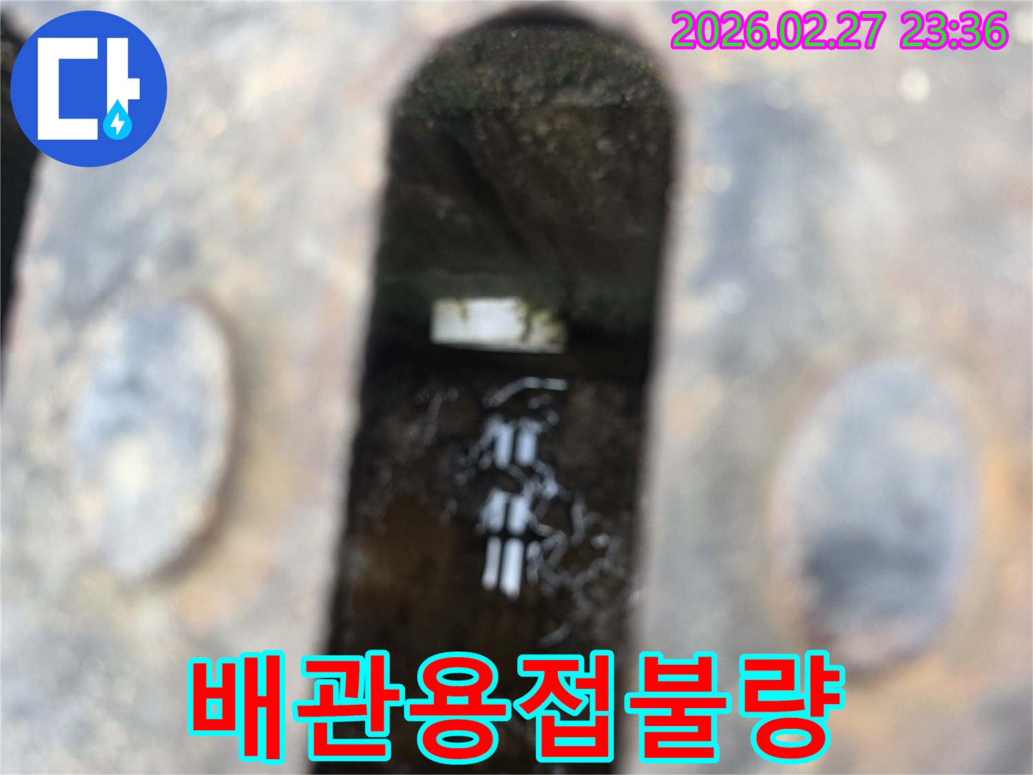 녹슨-철제-배수구-아래-고인-물과-물속에-잠긴-불량하게-용접된-배관-이음새가-보이는-누수-현장