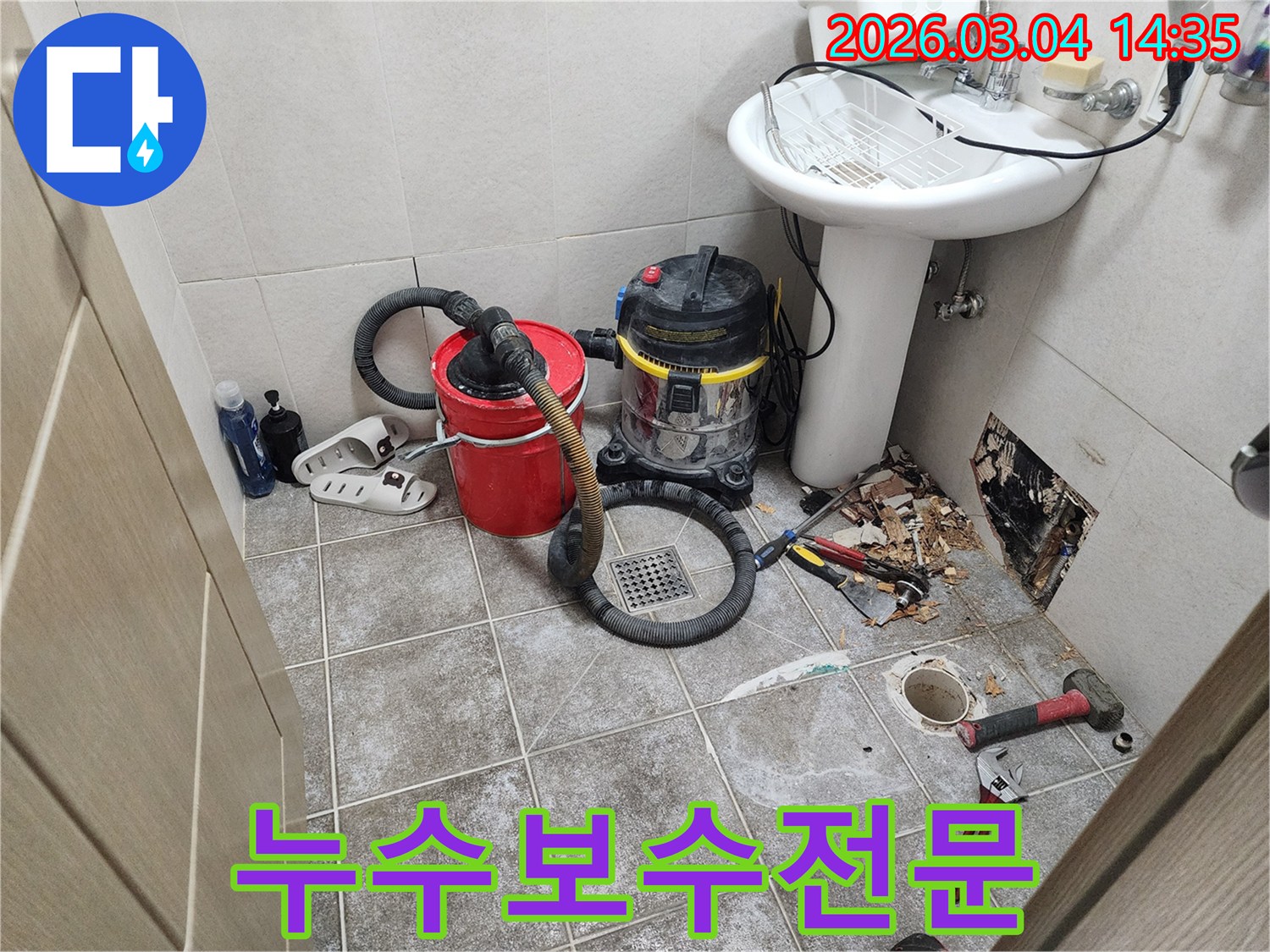 누수된 물을-제거하고-배관 압력을-테스트하기 위해-설치된-전문 장비들이-욕실 바닥에-놓여 있습니다