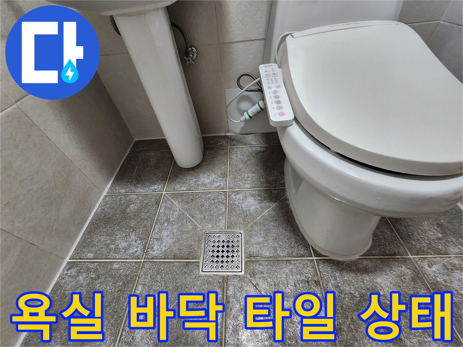 변기 주변의 회색 타일과 금속 배수구 덮개