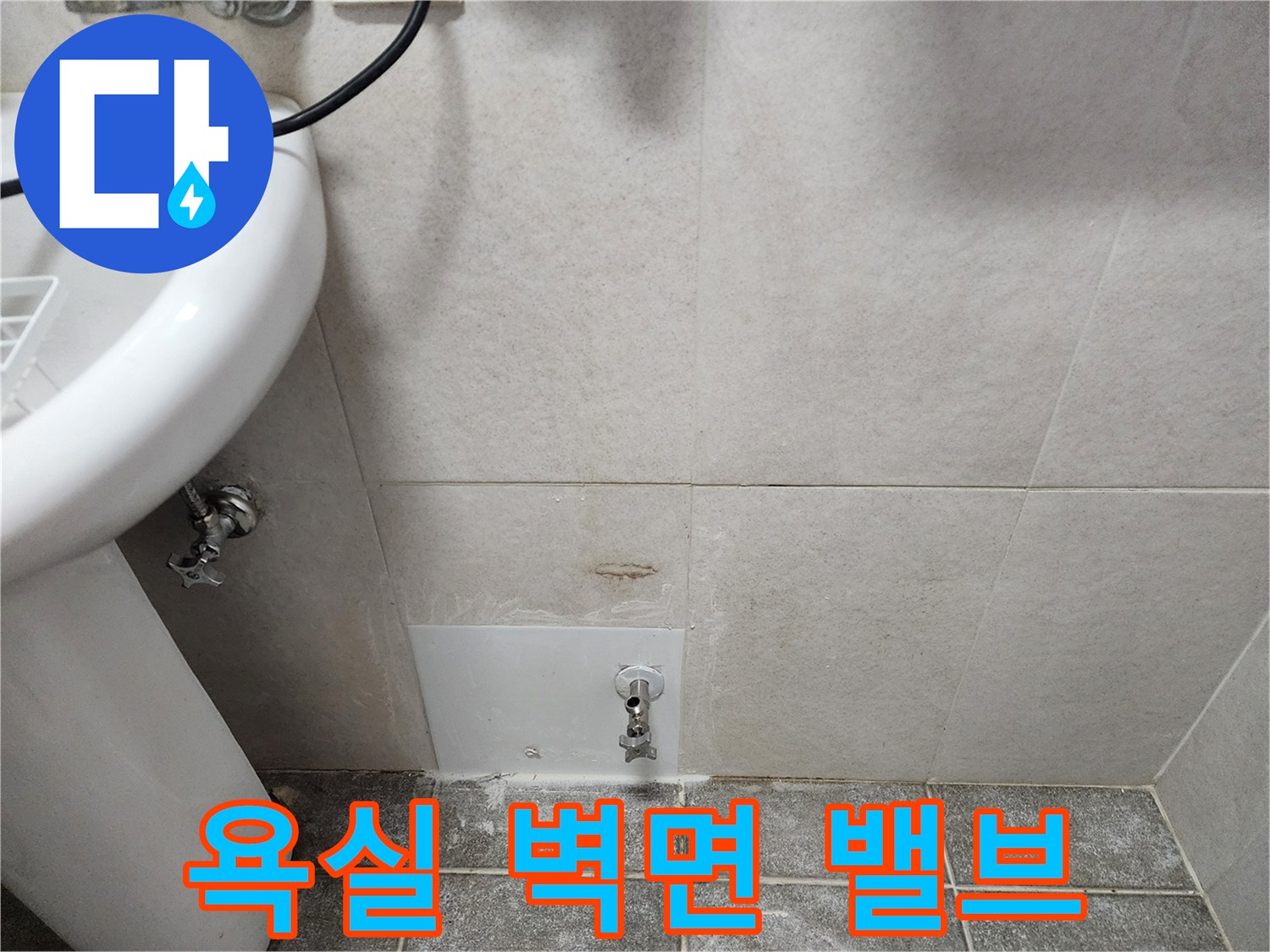 욕실 타일 벽면에 설치된 수도 밸브와 세면대 하단