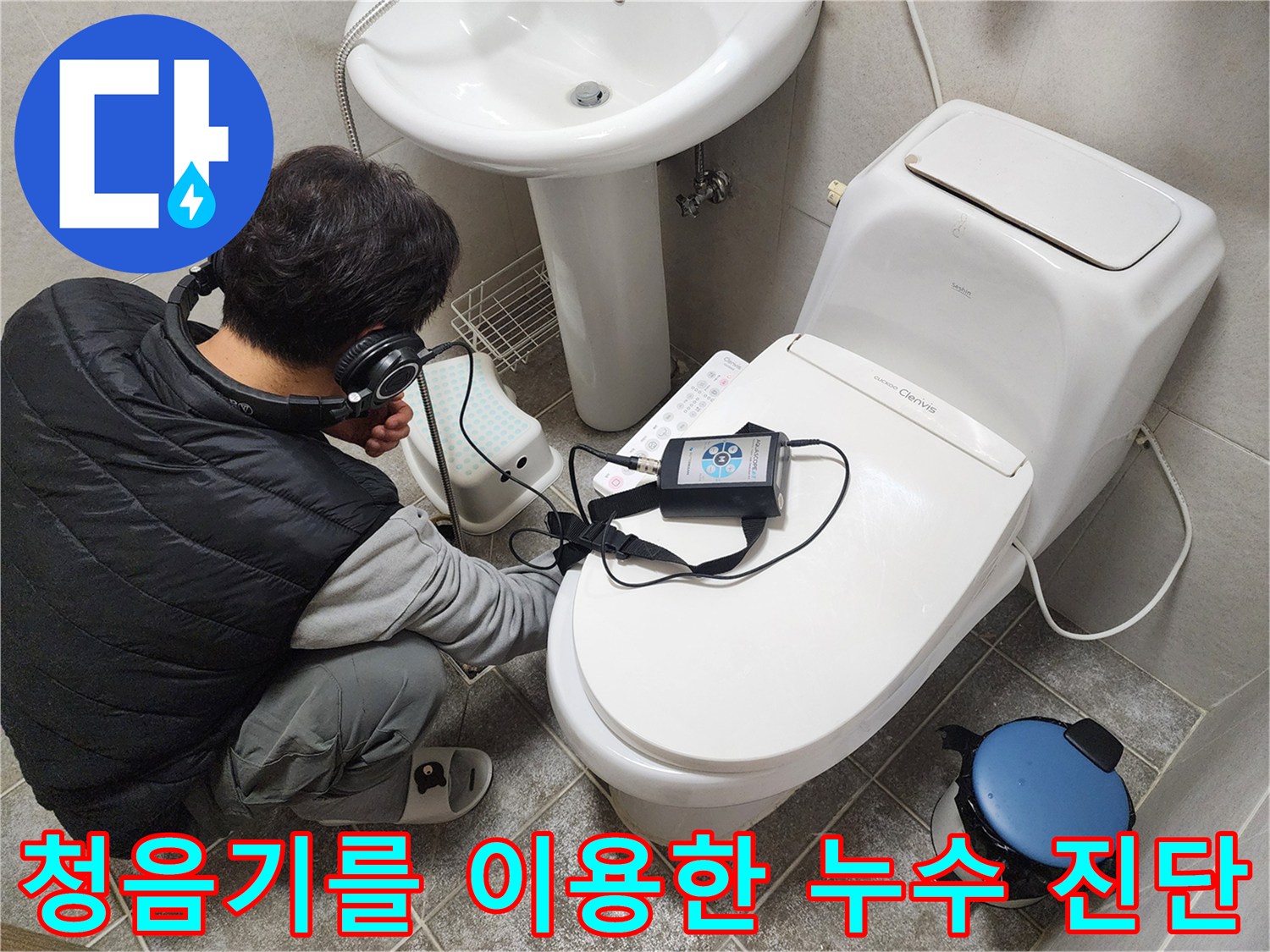화장실 변기 근처에서 헤드폰형 청음기를 사용하여 벽면 내부의 미세한 소리를 추적하는 모습
