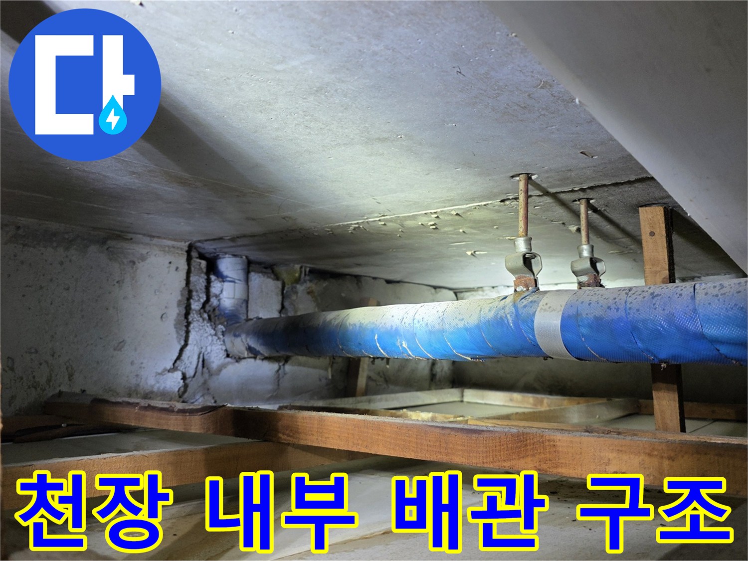목재 지지대 사이에 설치된 파란색 보온 배관과 천장 마감면 사진