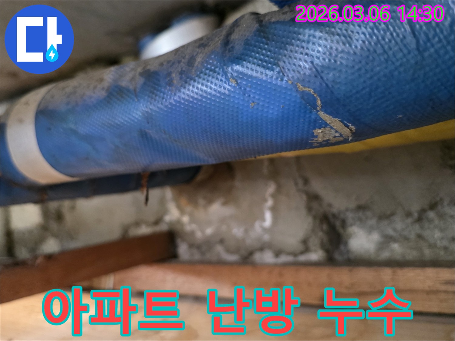 아파트 내부-파란색 난방 배관과-젖은 콘크리트 벽면-그리고 나무 지지대를-정밀하게 점검하는 모습