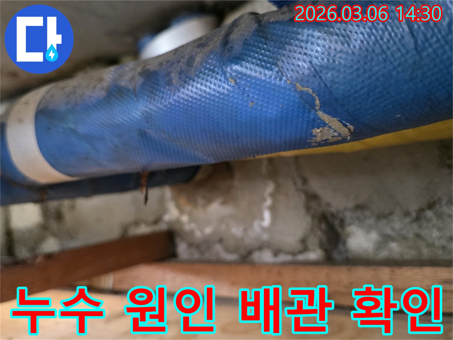 오래된 아파트 내부-파란색 배관과-젖은 콘크리트 벽면-그리고 나무 지지대를-정밀하게 점검하는 모습