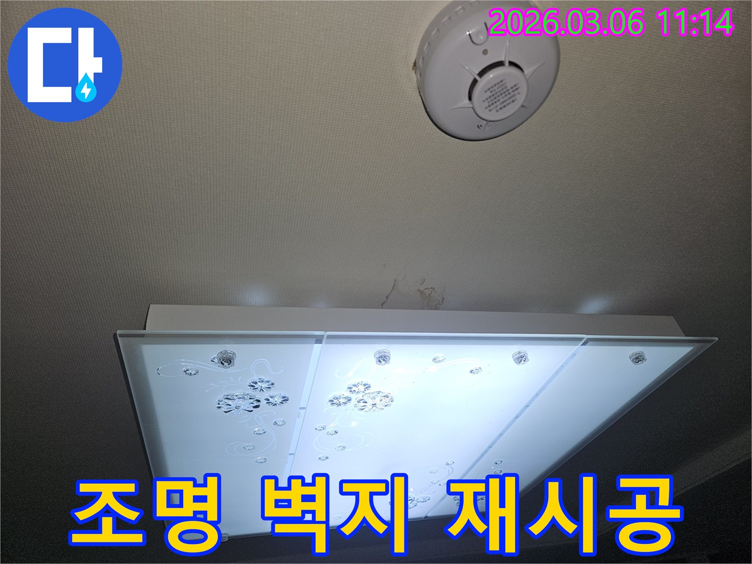 천장 조명 아래 누수로 손상된 벽지 흔적을-전문가가 확인하며 재시공 계획을 논의하는 모습