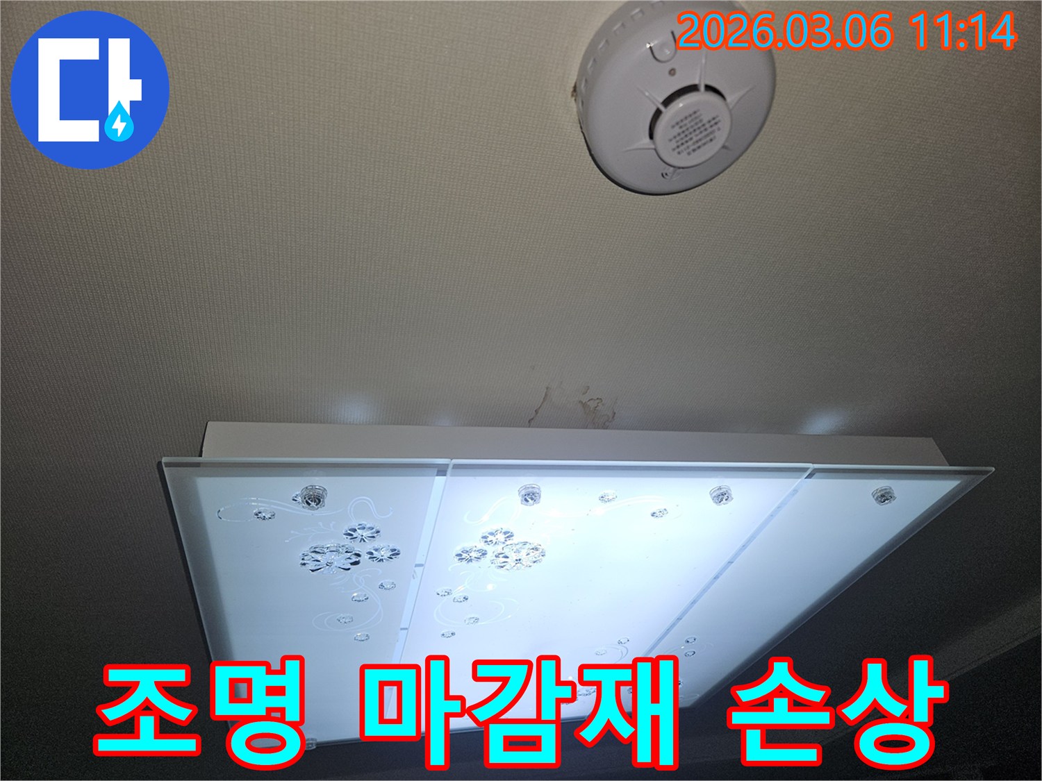 천장 조명 주변 마감재에 나타난 누수 피해 흔적을-전문가가 면밀히 확인하며 손상 정도를 파악하는 모습