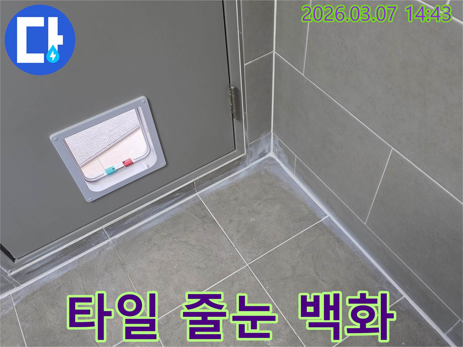 회색 타일의 줄눈과 벽면 하단-그리고 문 주변에 나타난-흰색 백화 현상은-물이 스며들고 있음을 나타내는 누수 증상입니다.