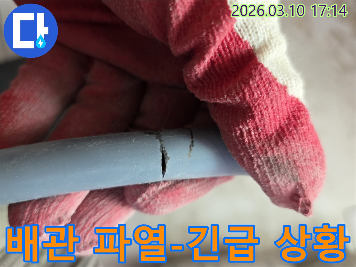 작업용 장갑을 착용한 손이-심하게 파열된 배관을 잡고-긴급한 누수 상황을 보여주고 있습니다