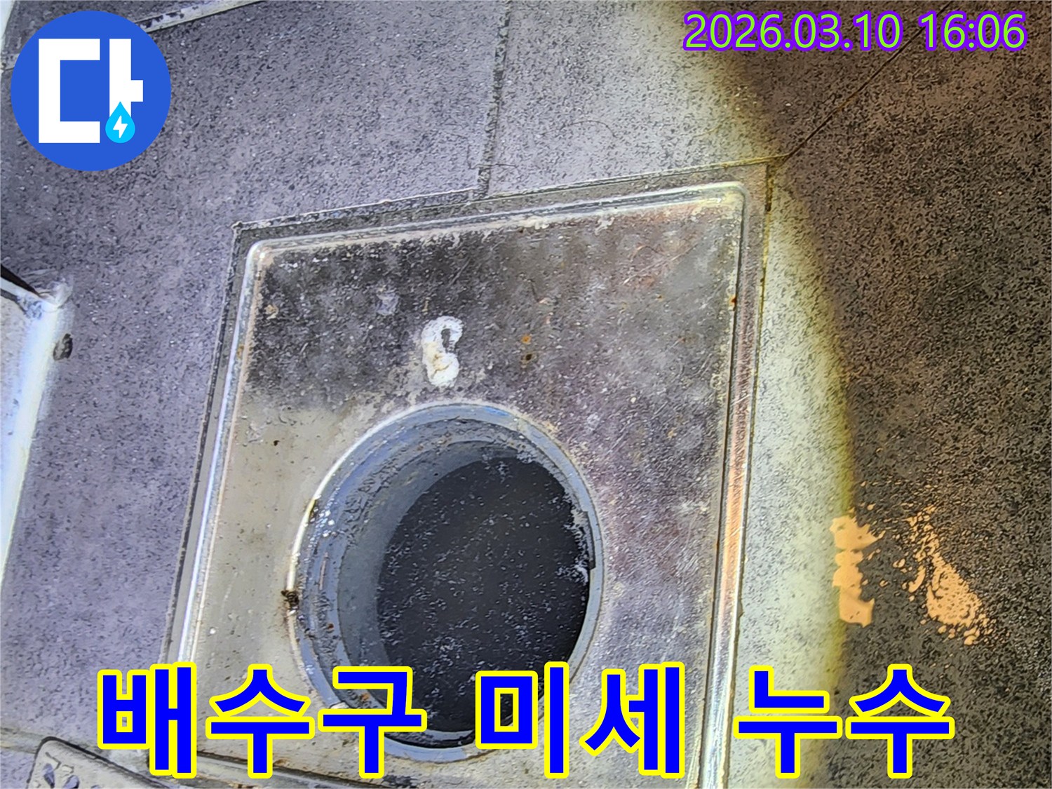 이 이미지는-서울 중구의 한 현장에서-육안으로 확인하기 어려운-배수구 주변의 미세 누수를-탐지하기 위해-배수구 커버를 열고-내부를 점검하는-과정을 보여줍니다