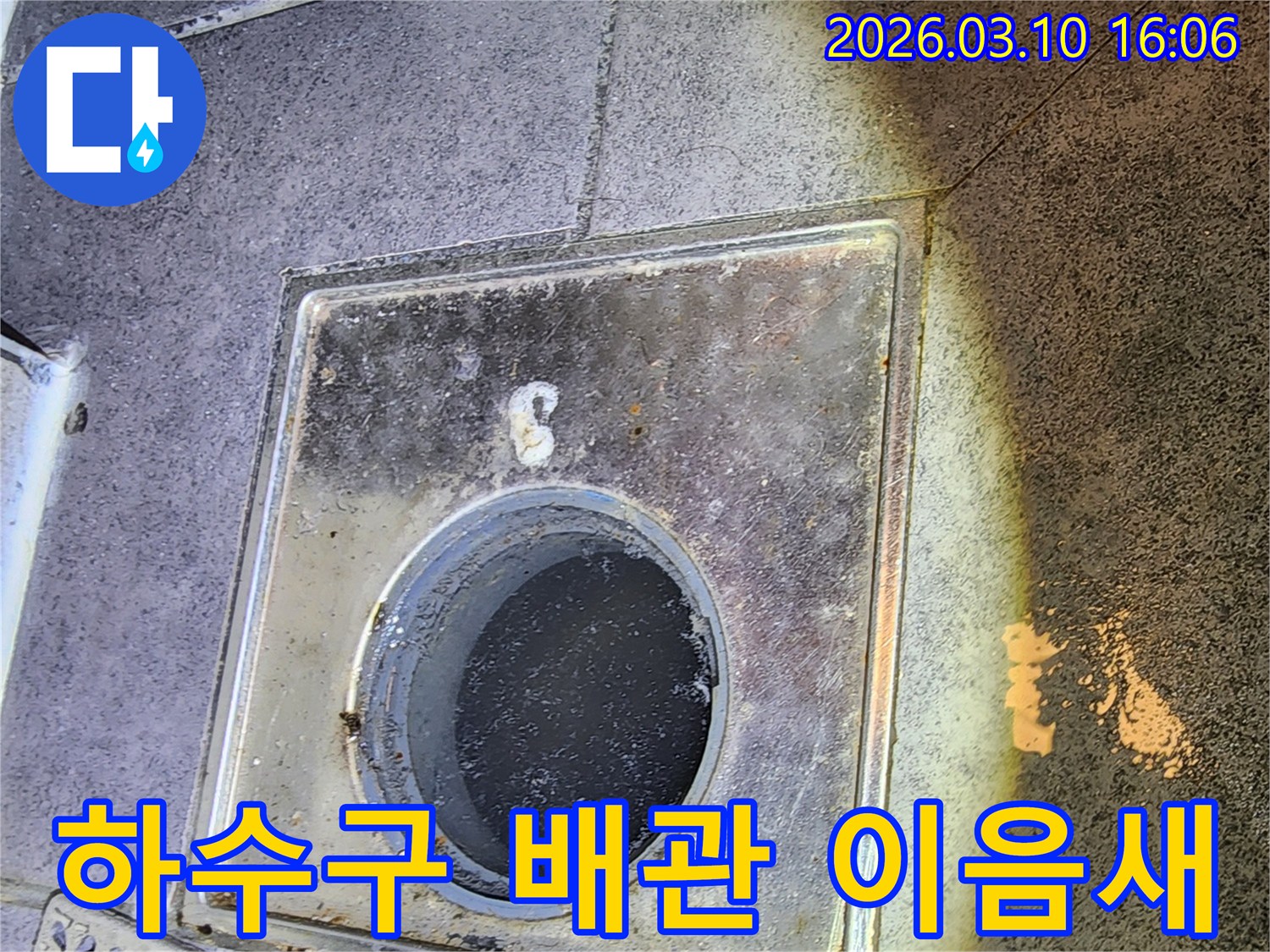 이 이미지는-서울 중구의 한 현장에서-하수구 배관 이음새의-누수 여부를 확인하기 위해-배수구 내부를-면밀히 점검하는-과정을 보여줍니다