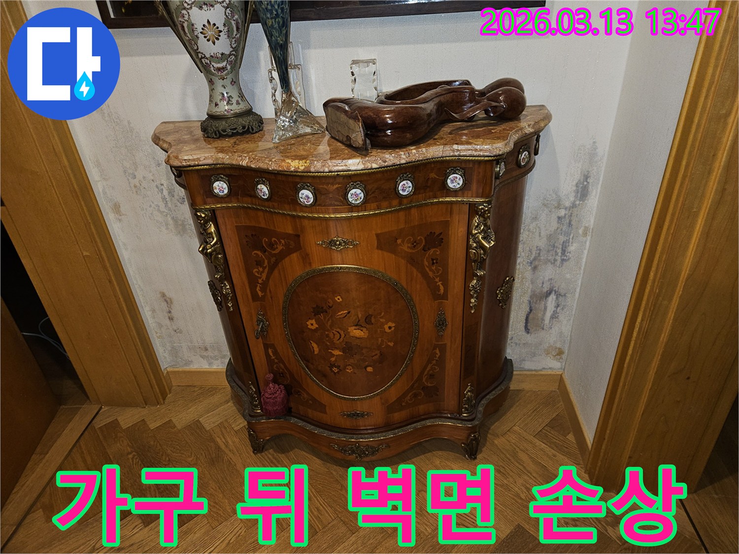 고급스러운 콘솔 가구 뒤-벽에 발생한-누수로 인한-벽지 변색과-곰팡이 흔적을 보여주는 사진