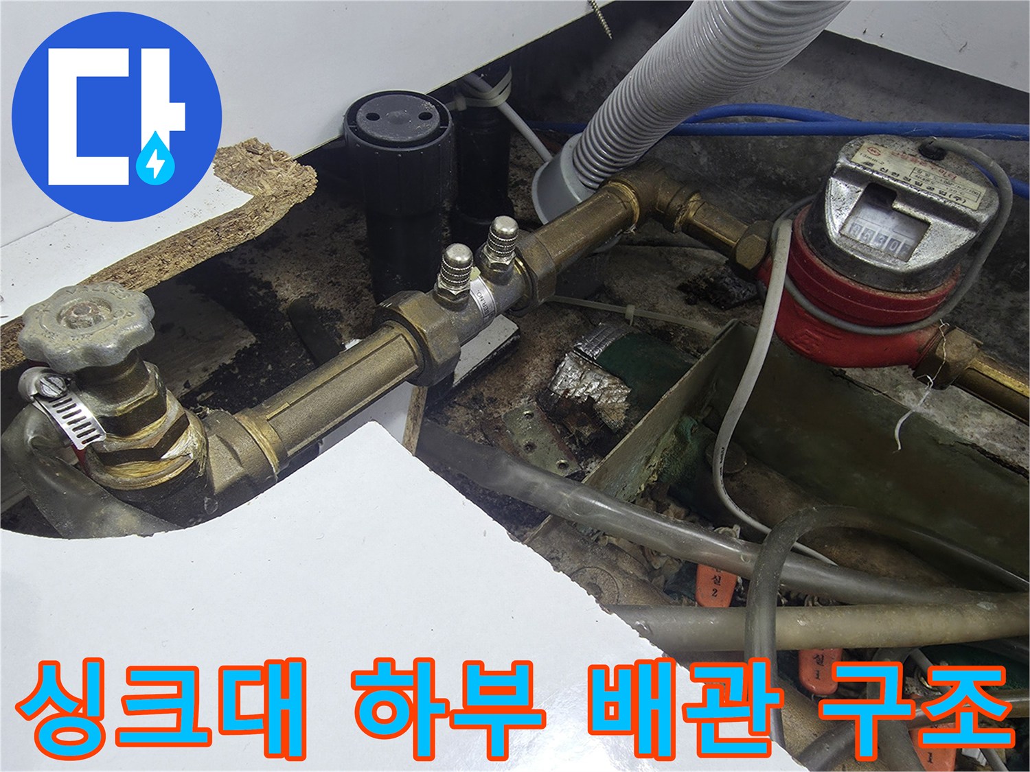 싱크대 하부의 수도 계량기와 금속 배관 부품들