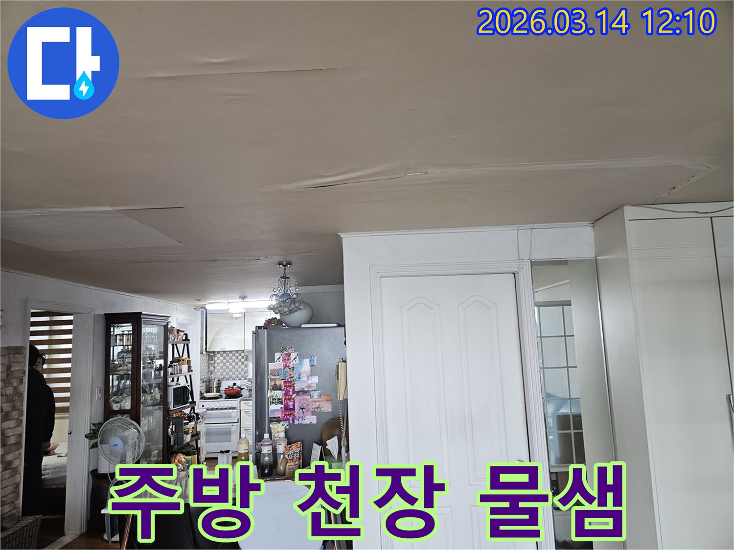 이 이미지는 주방과 연결된-거실 천장에 나타난-누수 현상을-보여줍니다-천장 마감재가 물에 젖어-변색되고-처진 모습은-주방 배관 문제로 인한-누수 가능성을-시사하며-정밀한 탐지가-필요합니다