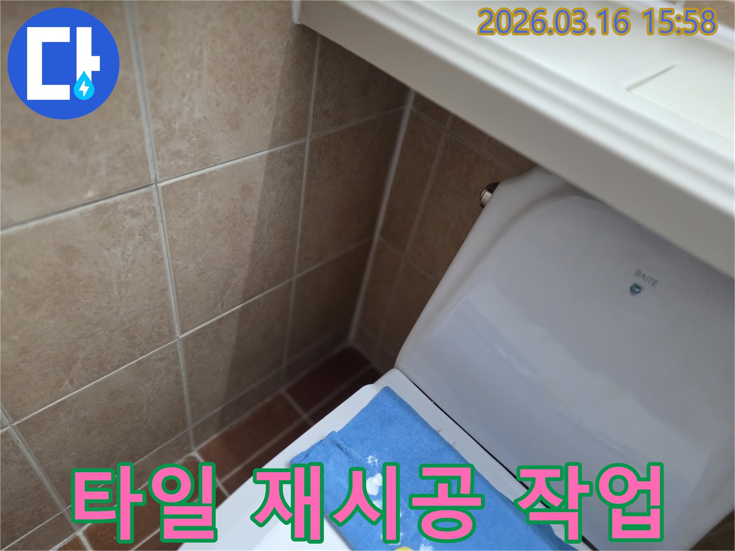 오산시 운암동의-한 욕실에서-변기 뒤편-벽면 타일의 젖음으로-누수 수리 후-손상되거나 제거했던 타일을-새롭게 재시공하는-현장을 보여주는-사진입니다.
