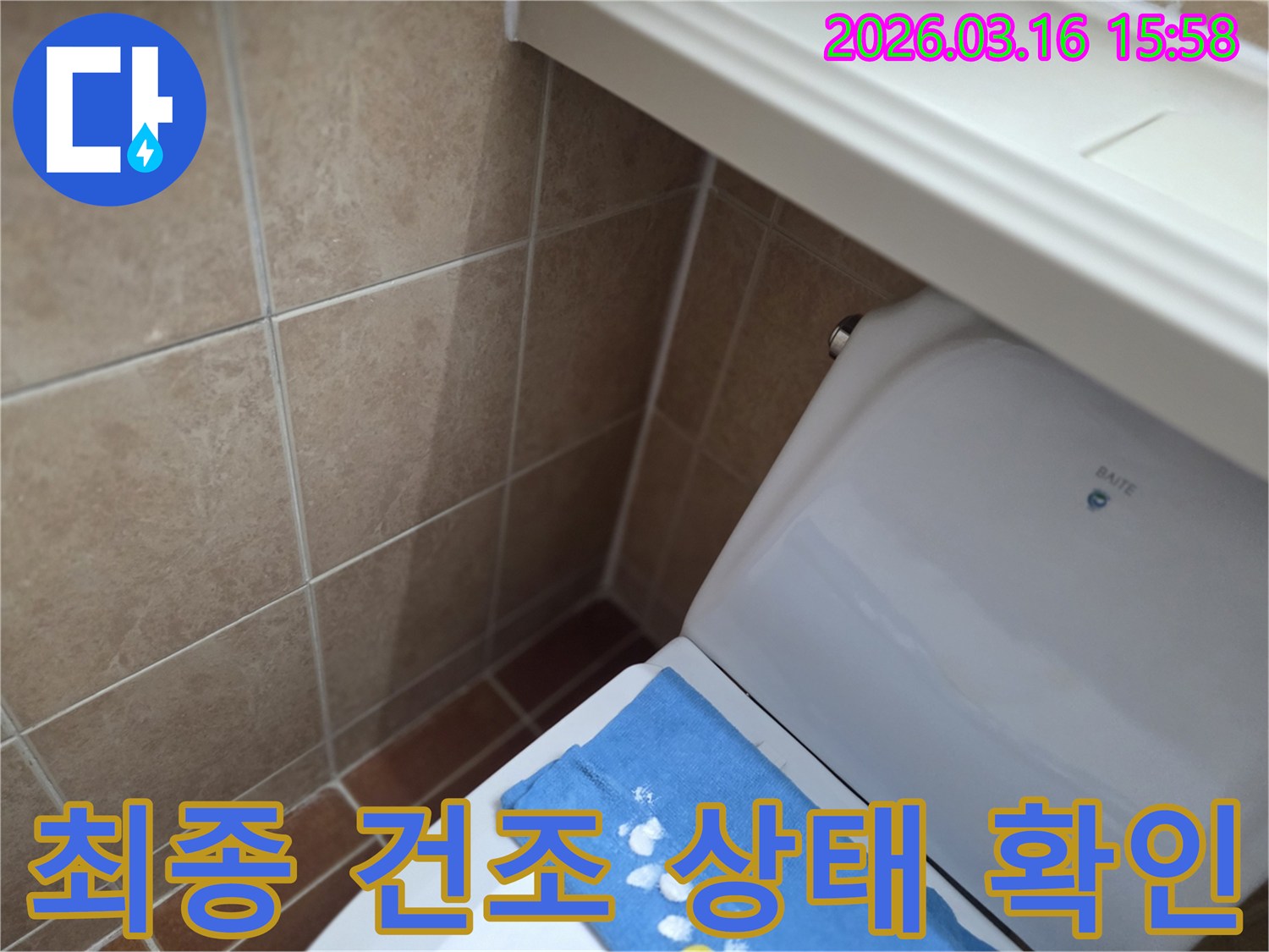 오산시 운암동의-한 욕실에서-변기 뒤편-벽면 타일의 젖음으로-누수 수리 후-최종적으로 건조 상태를-확인하는 현장을-보여주는 사진입니다.