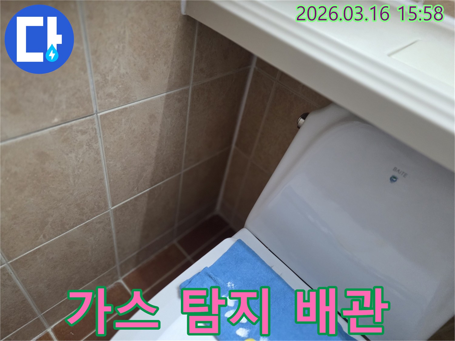 오산시 운암동의-한 욕실에서-변기 뒤편-벽면 타일의 젖음으로-특수 가스 탐지기를 사용하여-배관 누수를-확인하는 현장을-보여주는 사진입니다.