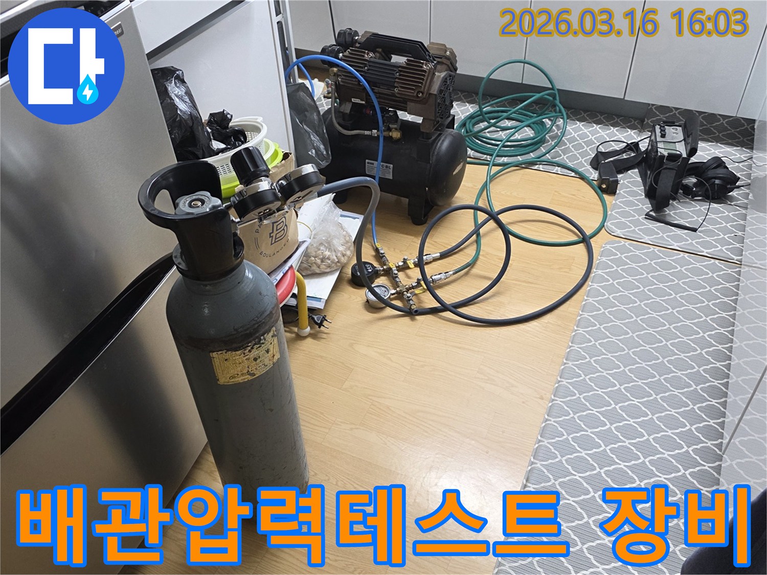 배관의 미세한 누수 지점을 찾아내기 위해-가스통과 압력계를 연결하여-정밀 검사를 준비하는 모습입니다