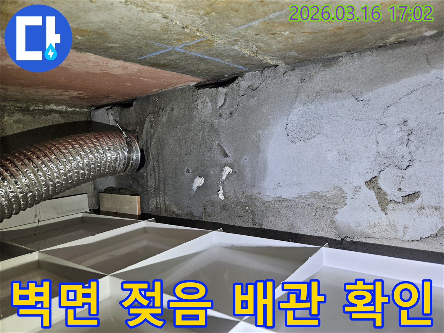 누수-전문가가-벽면의-젖은-부분과-인접한-배관-연결부를-꼼꼼히-살펴보는-현장-사진입니다