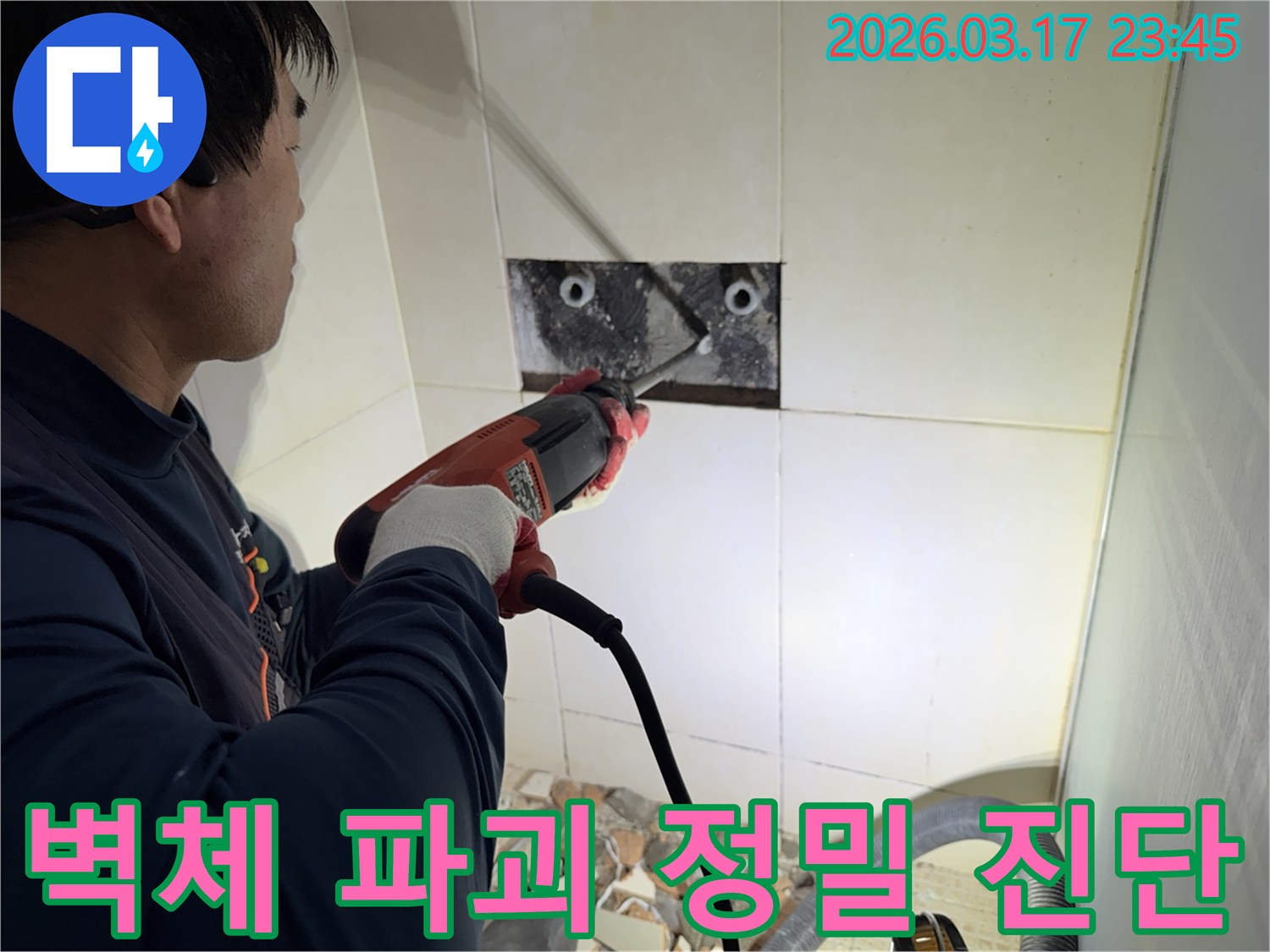 누수 공사 전문가가 욕실 벽면의 타일을 조심스럽게 파쇄하여-누수 원인을 찾기 위한 배관 확인 작업을 진행하는 모습입니다.