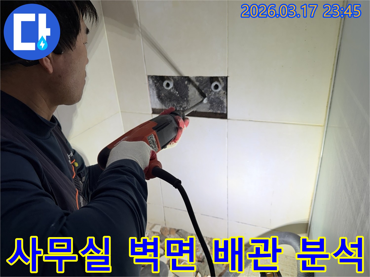 누수 전문가가 사무실 벽면 타일을 깨끗하게 파쇄하며-누수 원인인 배관의 문제점을 정밀하게 분석하는 작업을 진행 중입니다.