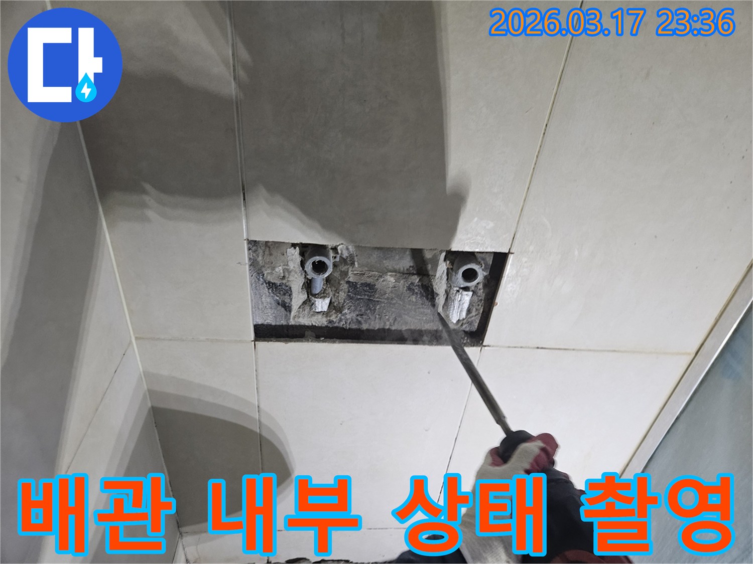 누수 지점을-정확히 찾기 위해-타일 벽면을-개방하여-배관 내부 상태를-면밀히-점검하고-촬영하는 작업 현장